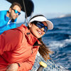 Lächelnde Frau mit roter Jacke und Sonnenbrille beim Segeln, Mann mit blauer Jacke im Hintergrund, Key Visual Jahrestagung Junge DLG 2025